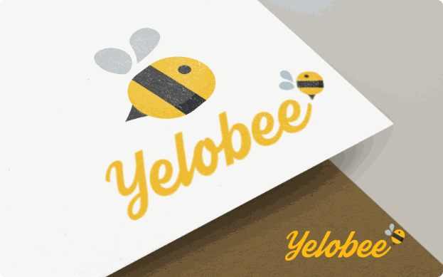 Close-up mockup of the Yelobee bee symbol and wordmark on paper, with a smaller lock-up on a wooden surface