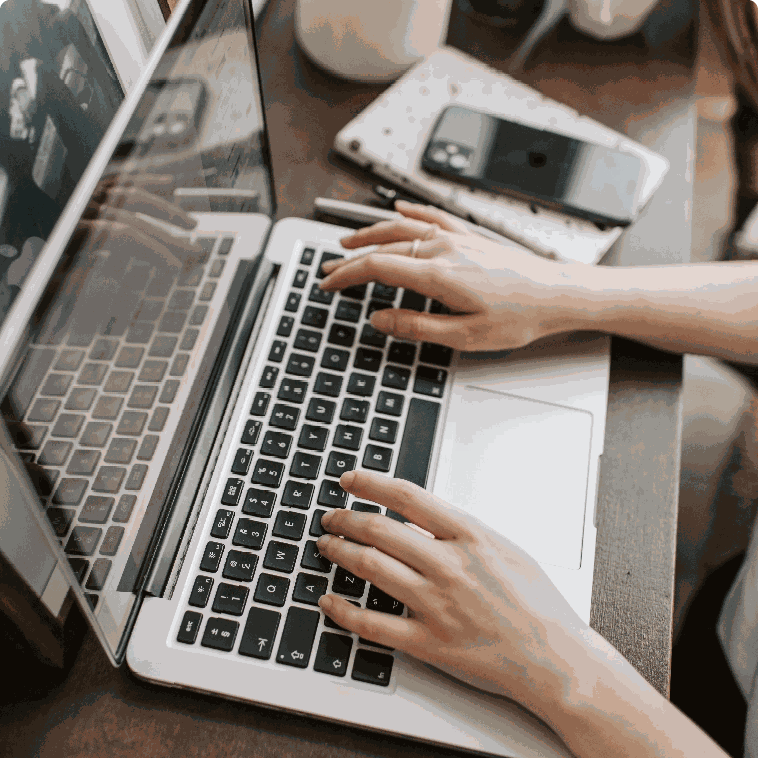 Hands typing on a laptop beside a phone, planning campaigns at a digital marketing agency Penang office