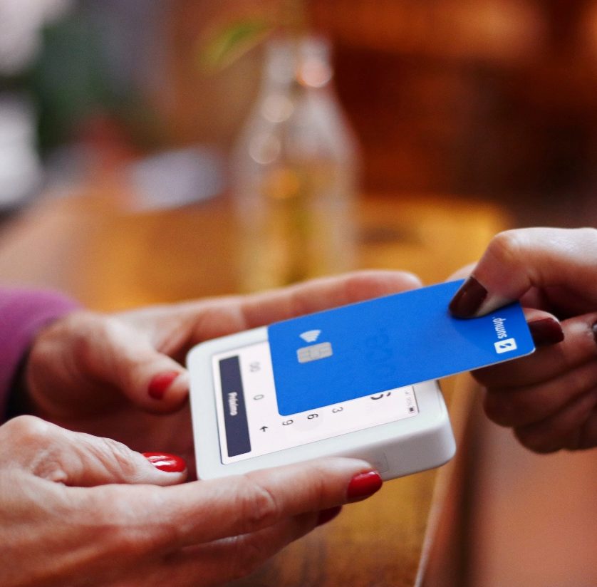 Customer paying by card at a shop counter, a reminder that payment features shape website cost