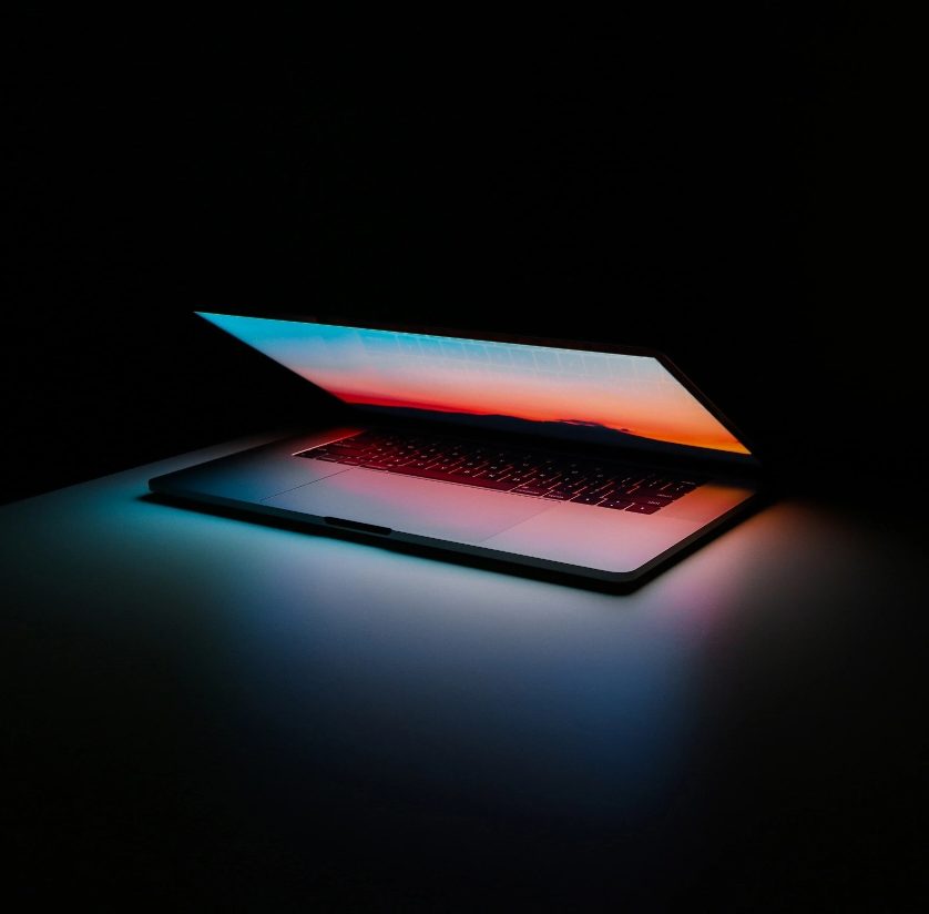 Half-open laptop glowing in a dark room, representing reliable website hosting Malaysia from Spacebar